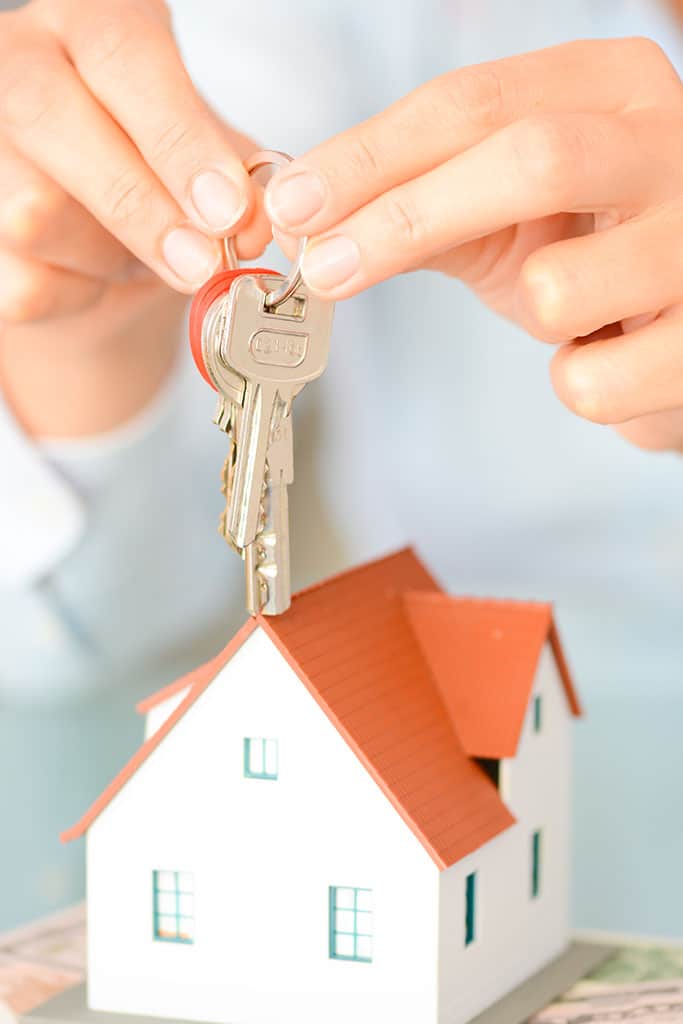 Buying a house concept with woman hands holding a model house and keys