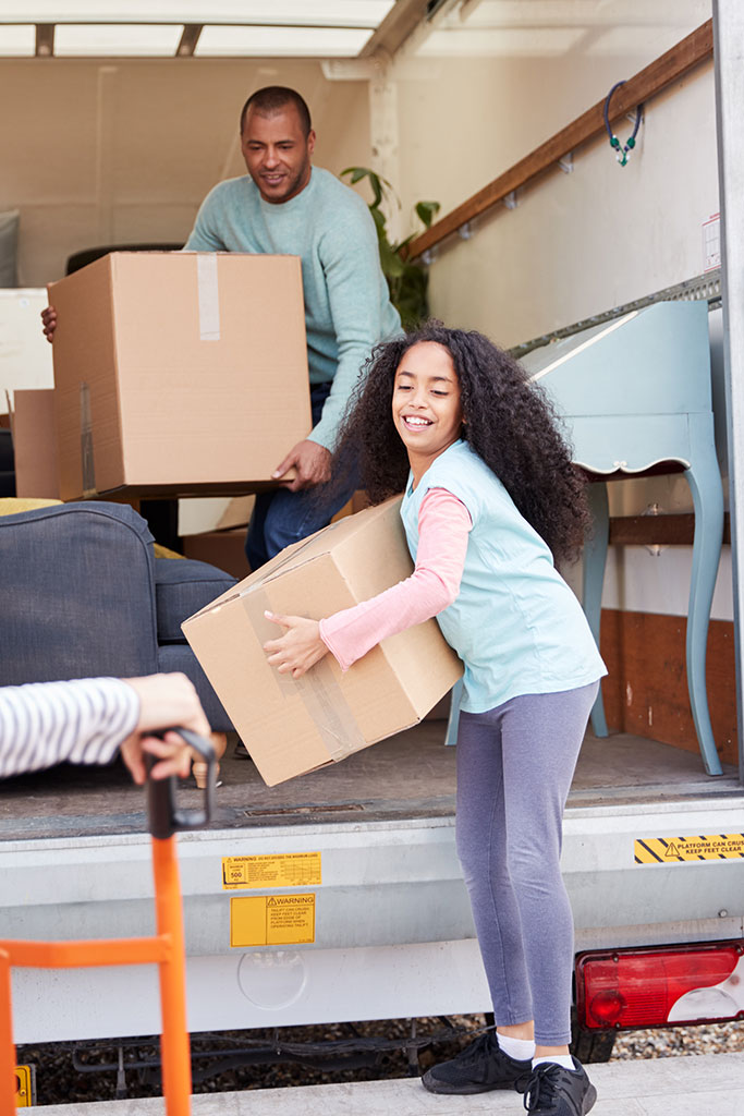 Family Unloading Furniture From Removal Truck Into New Home